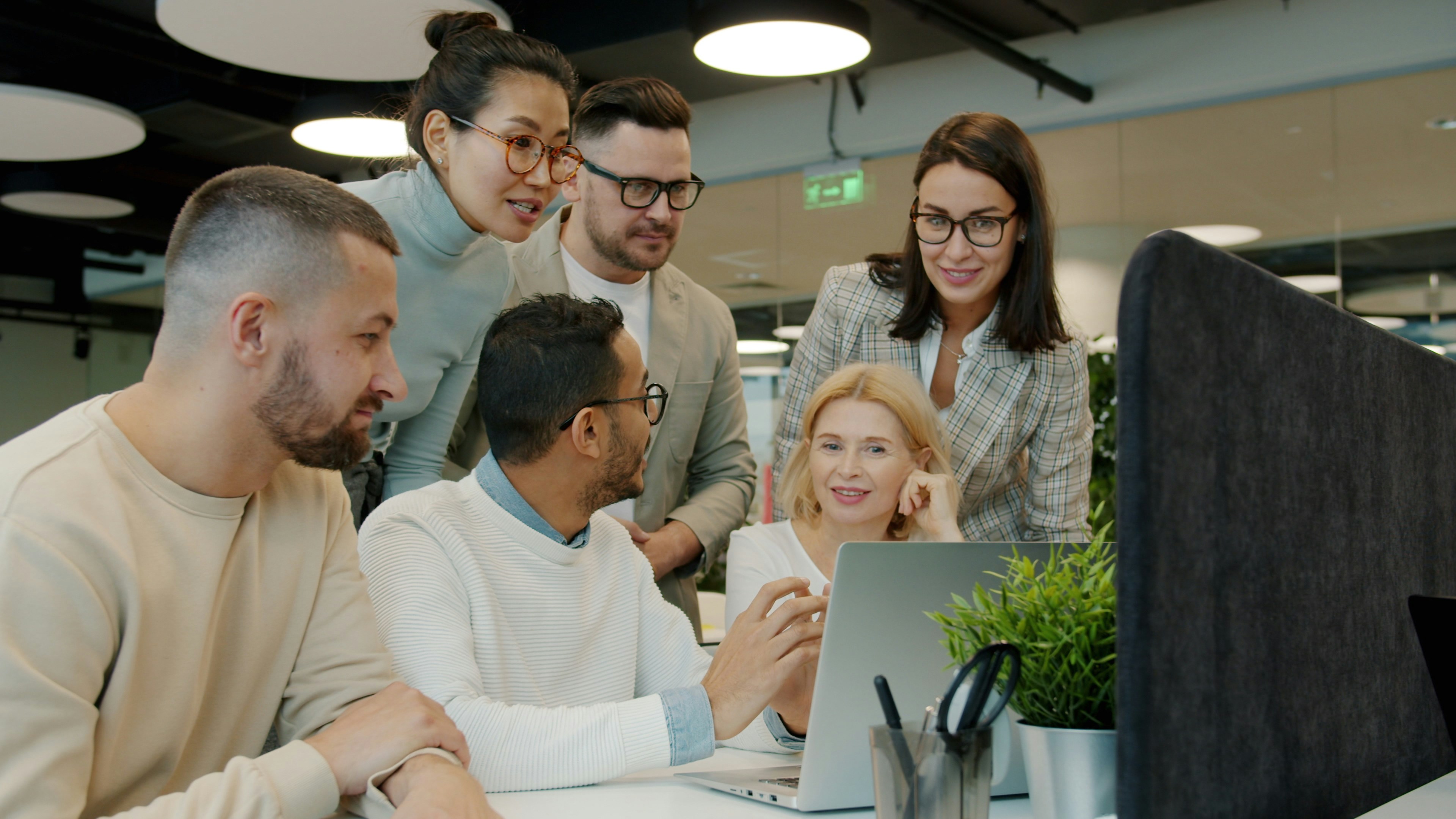 Diverse team collaborating around a laptop in an office. Photo by Vitaly Gariev on Unsplash.